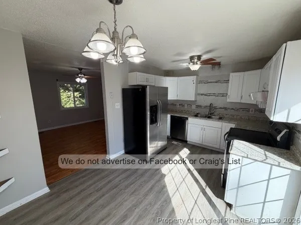 a kitchen with stainless steel appliances granite countertop a refrigerator oven a sink dishwasher and white cabinets with wooden floor