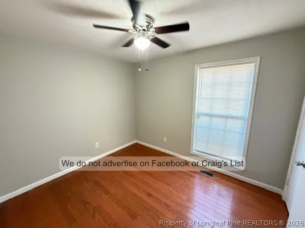 an empty room with a ceiling fan and wooden floor