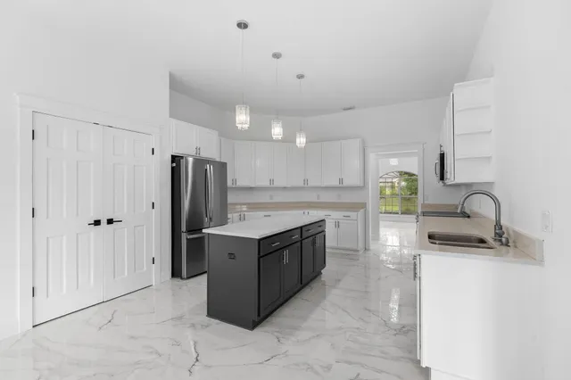 a kitchen with granite countertop a refrigerator and a stove top oven