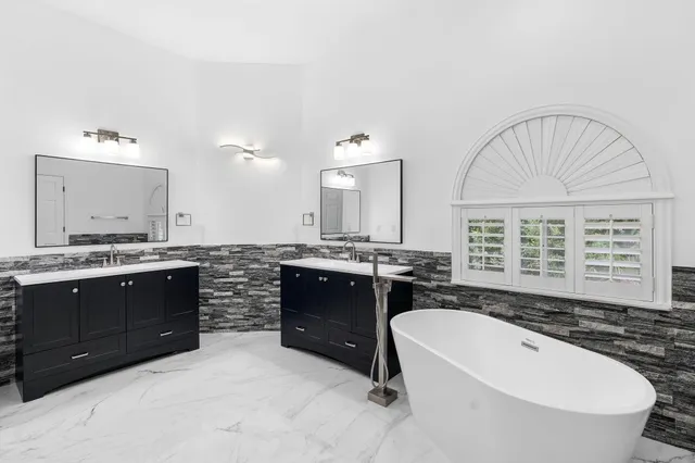a spacious bathroom with a tub sink and mirror