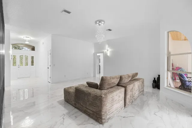 a large white kitchen with kitchen island a sink a stove and a refrigerator with wooden floor