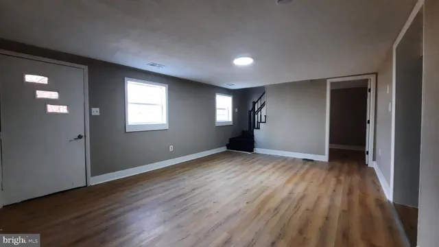 an empty room with wooden floor and windows
