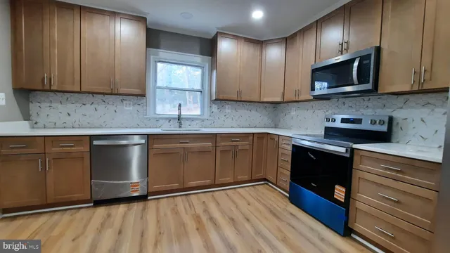 a kitchen with granite countertop wooden cabinets stainless steel appliances and a sink
