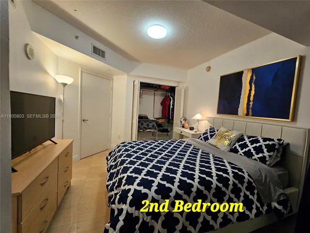 a bedroom with a bed and a flat tv screen on dresser