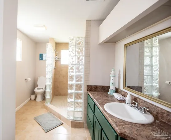 a bathroom with a granite countertop sink a toilet a mirror and a shower