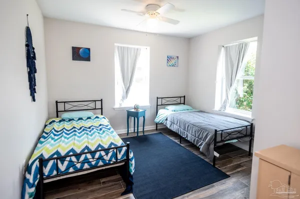 a bedroom with a bed next to a window with a chair