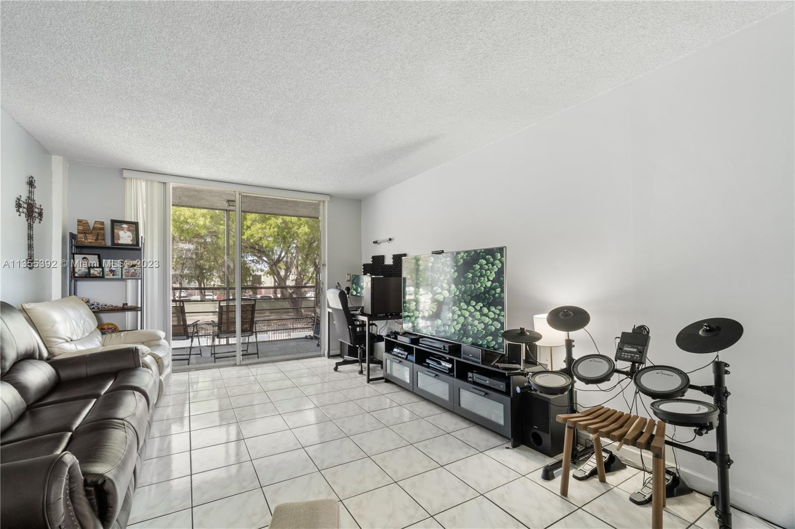 14140 Southwest 84th Street, Unit 208H Miami, FL 33183 - Photo 7 of 29 a living room with furniture and a flat screen tv