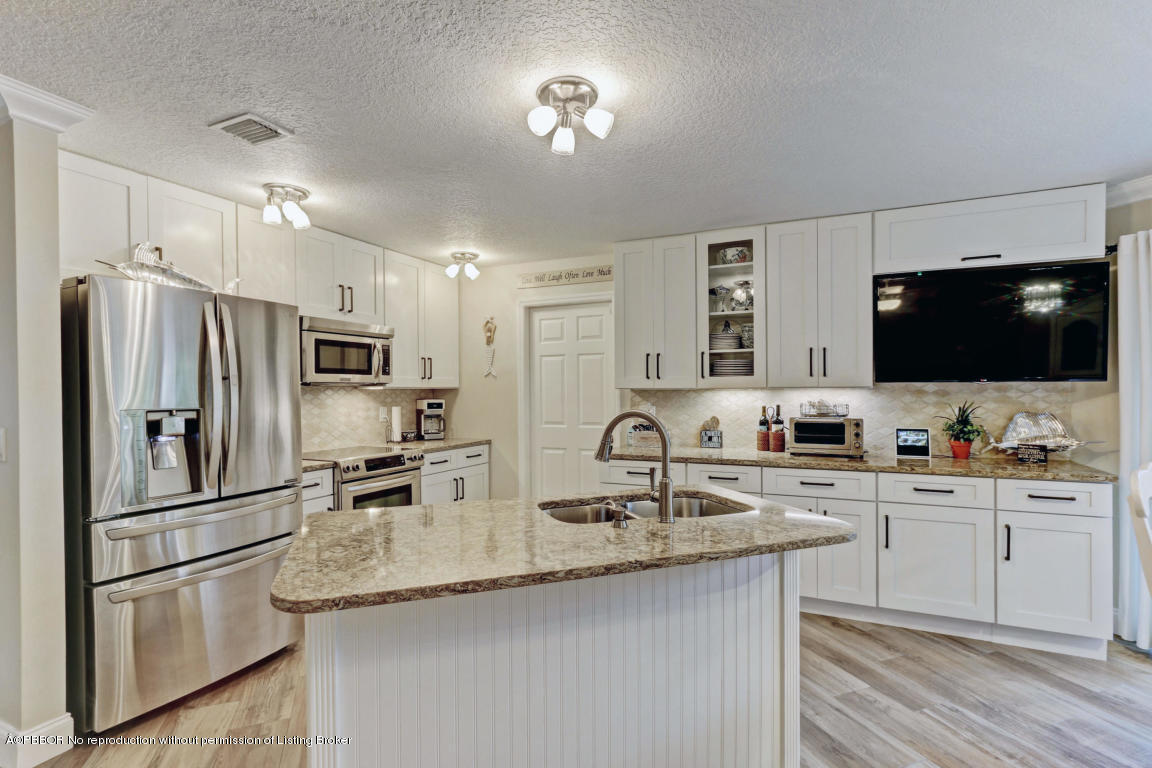 18905 Southeast County Line Road Jupiter, FL 33469 - Photo 23 of 74 a kitchen with stainless steel appliances a sink stove refrigerator and cabinets