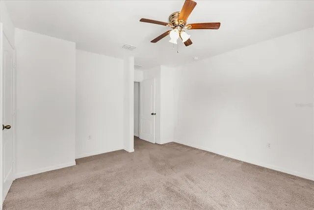 an empty room with windows and ceiling fan