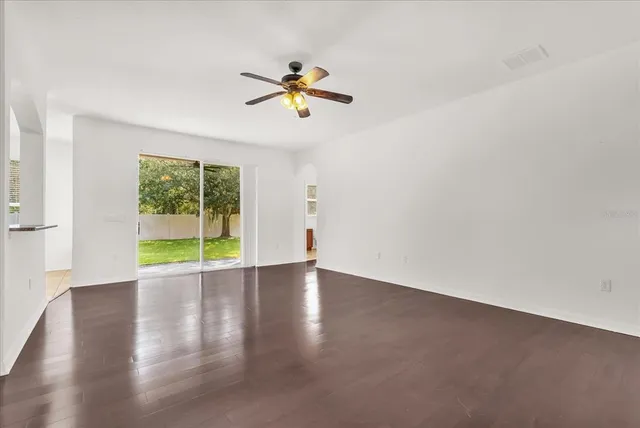 a view of an empty room with a kitchen and wooden floor