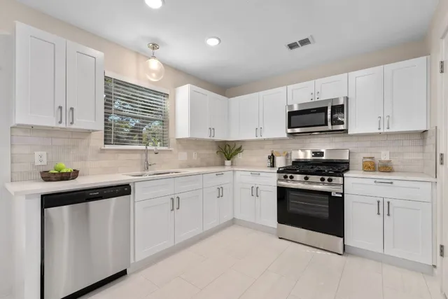 a kitchen with granite countertop white cabinets and white stainless steel appliances