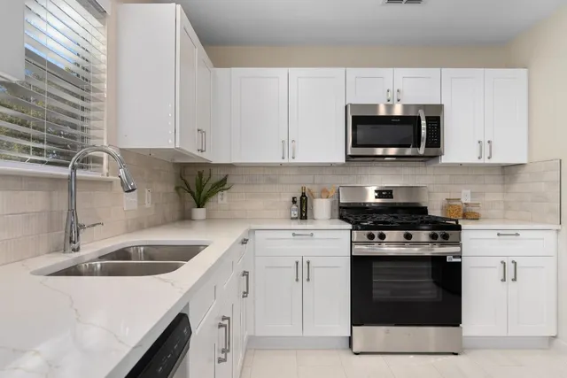 a kitchen with white cabinets and stainless steel appliances
