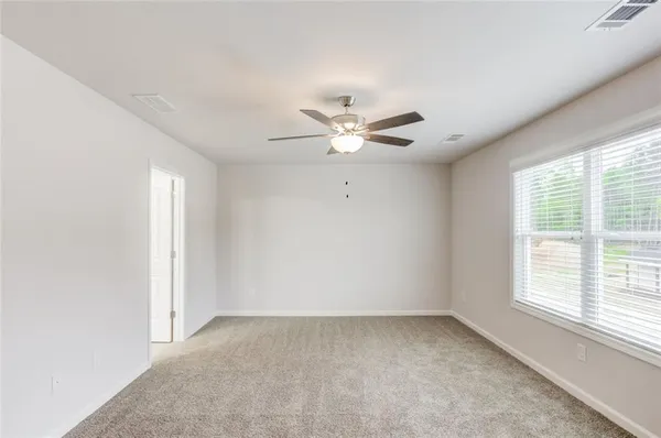 an empty room with windows and fan