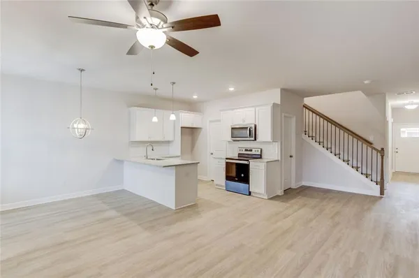 a large white kitchen with kitchen island a sink dishwasher a stove and a refrigerator with wooden floor