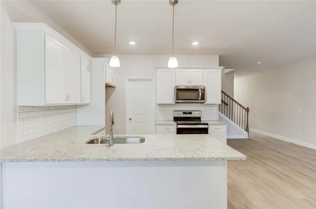 a kitchen with stainless steel appliances granite countertop a sink a stove and a granite counter top