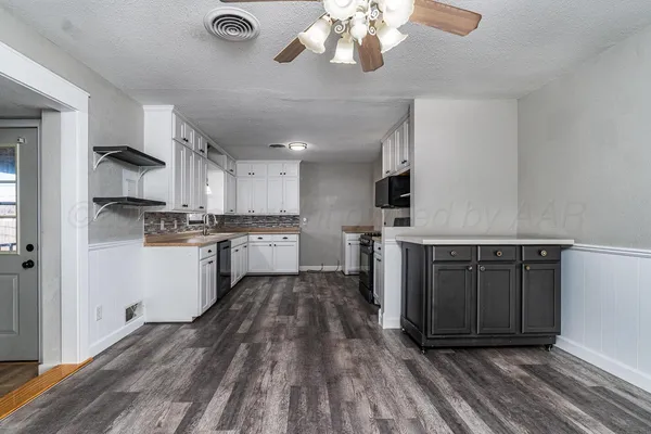 a kitchen with stainless steel appliances granite countertop a stove top oven a sink dishwasher and a refrigerator with wooden floor