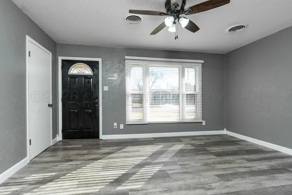 a view of an empty room with a window and a chandelier fan