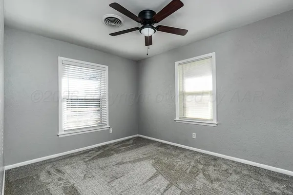 an empty room with a window and a fan