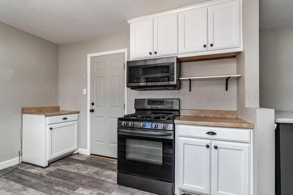 a kitchen with cabinets appliances and a wooden floor