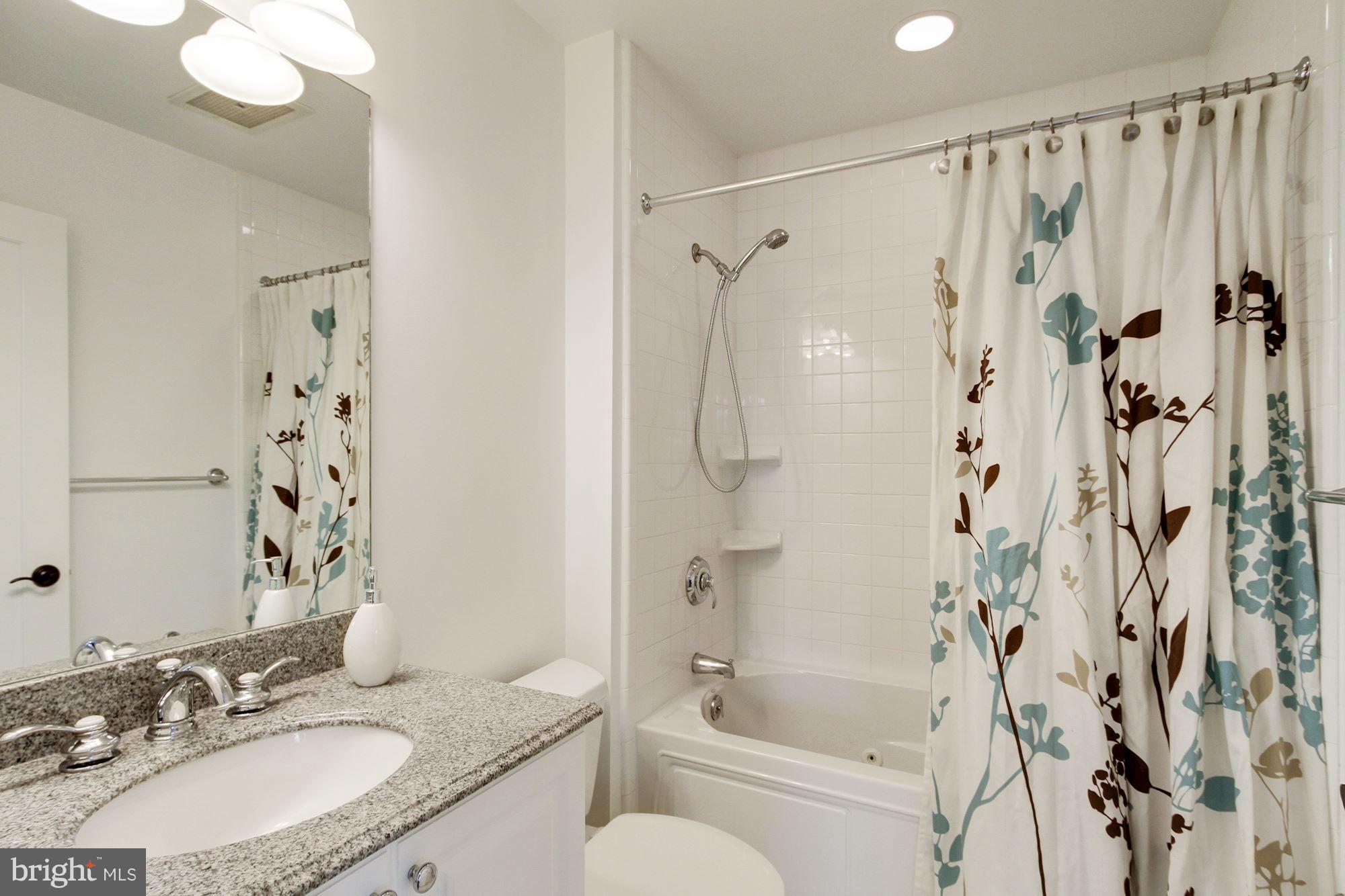 2902 Porter Street Northwest, Unit 21 Washington, DC 20008 - Photo 16 of 18 a bathroom with a granite countertop sink a toilet and shower