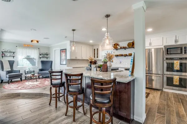 a kitchen with stainless steel appliances a dining table chairs refrigerator and sink