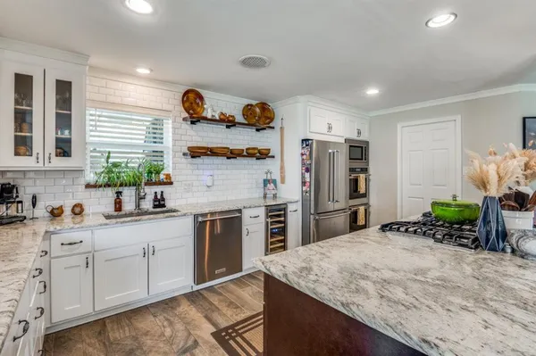 a kitchen with granite countertop a sink stainless steel appliances and cabinets