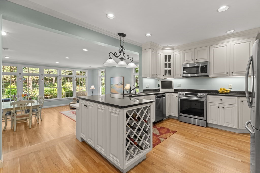 220 Perkins Row Topsfield, MA 01983 - Photo 7 of 42 a kitchen with stainless steel appliances granite countertop a stove top oven a sink dishwasher a dining table and chairs with wooden floor