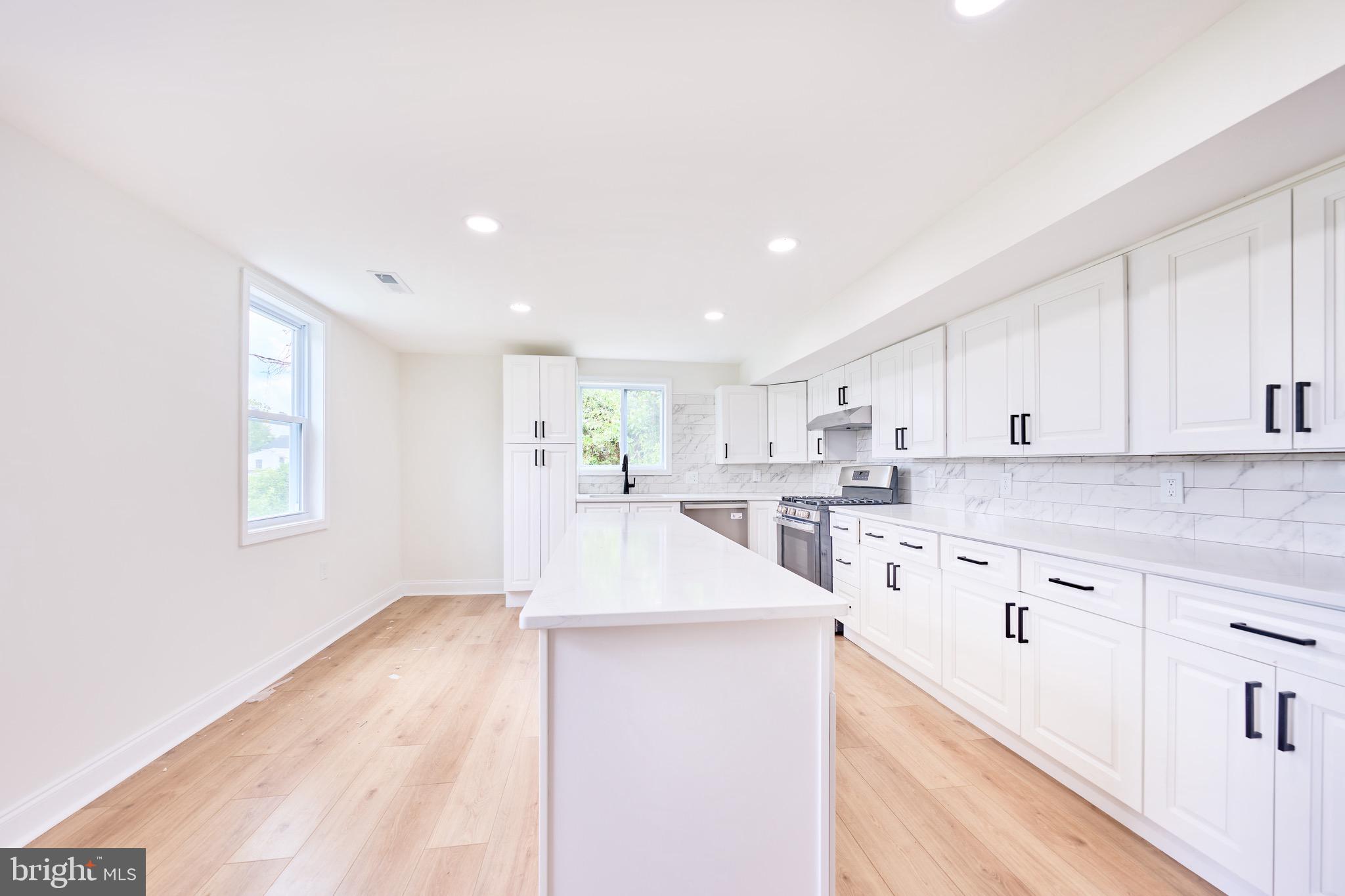 3511 Old Frederick Road Baltimore, MD 21229 - Photo 12 of 43 a view of a kitchen with kitchen island stainless steel appliances wooden floor cabinets and a window