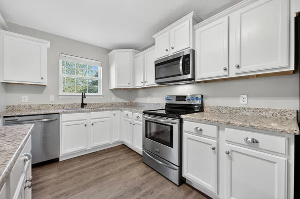 a kitchen with granite countertop white cabinets a sink and white appliances
