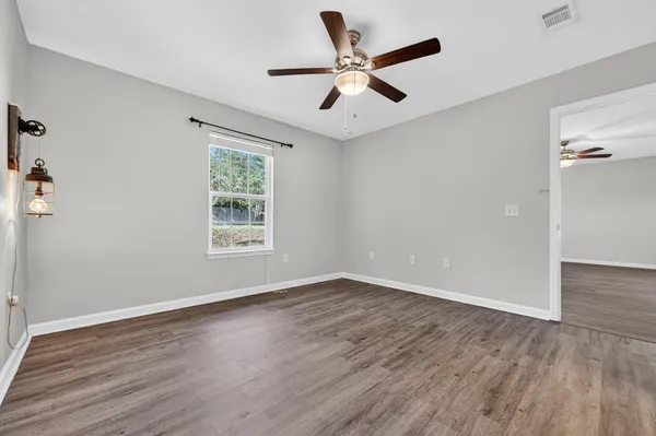 a view of an empty room with wooden floor and a window