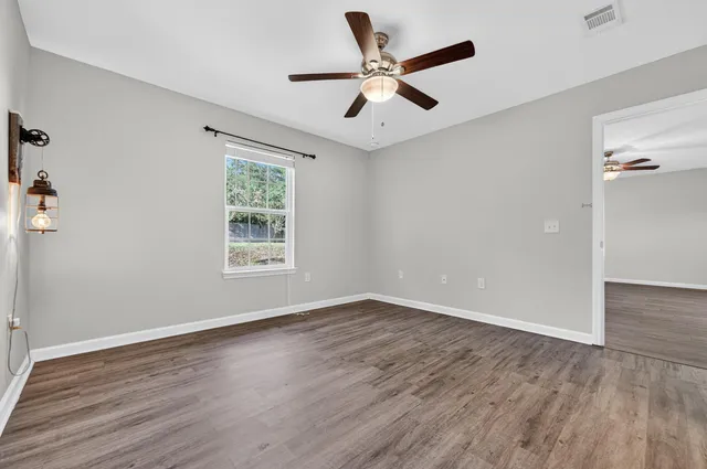 a view of an empty room with wooden floor and a window