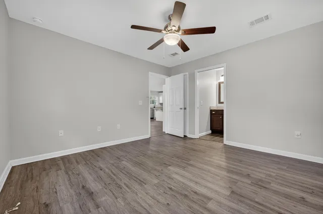 an empty room with wooden floor and ceiling fan