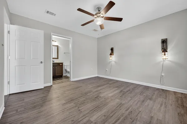 an empty room with wooden floor and a ceiling fan