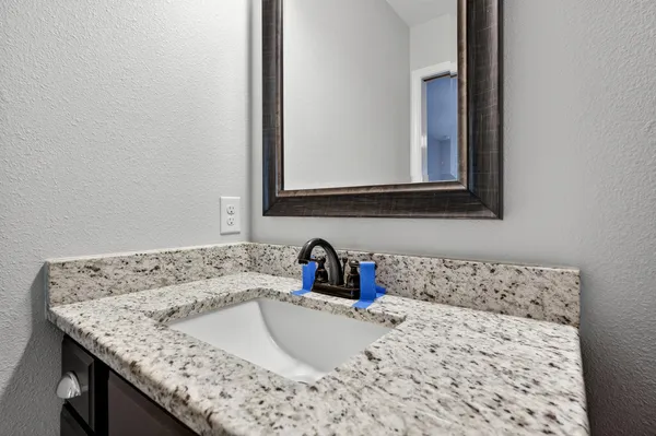 a bathroom with a granite countertop sink and a window