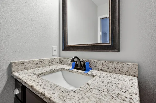 a bathroom with a granite countertop sink and a window