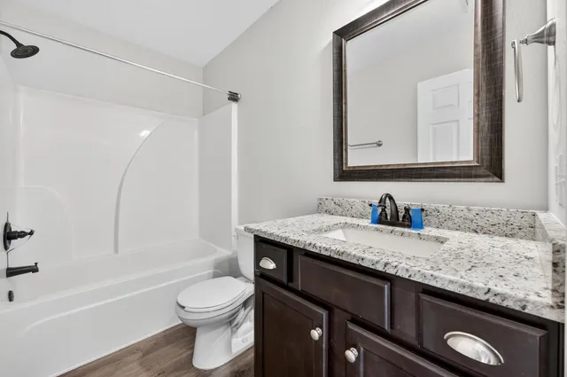 a bathroom with a granite countertop sink a toilet and a mirror