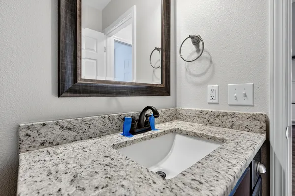 a bathroom with a granite countertop sink a mirror and shower