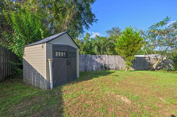 a view of backyard with large trees and wooden fence
