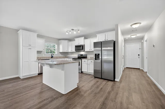a kitchen with a refrigerator a sink dishwasher a refrigerator and white cabinets with wooden floor