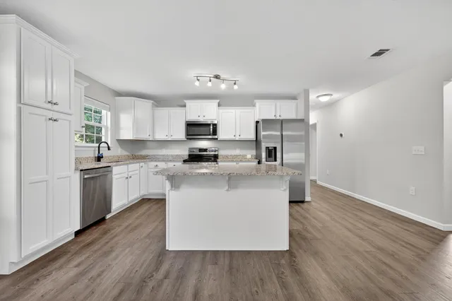 a kitchen with kitchen island white cabinets stainless steel appliances and sink