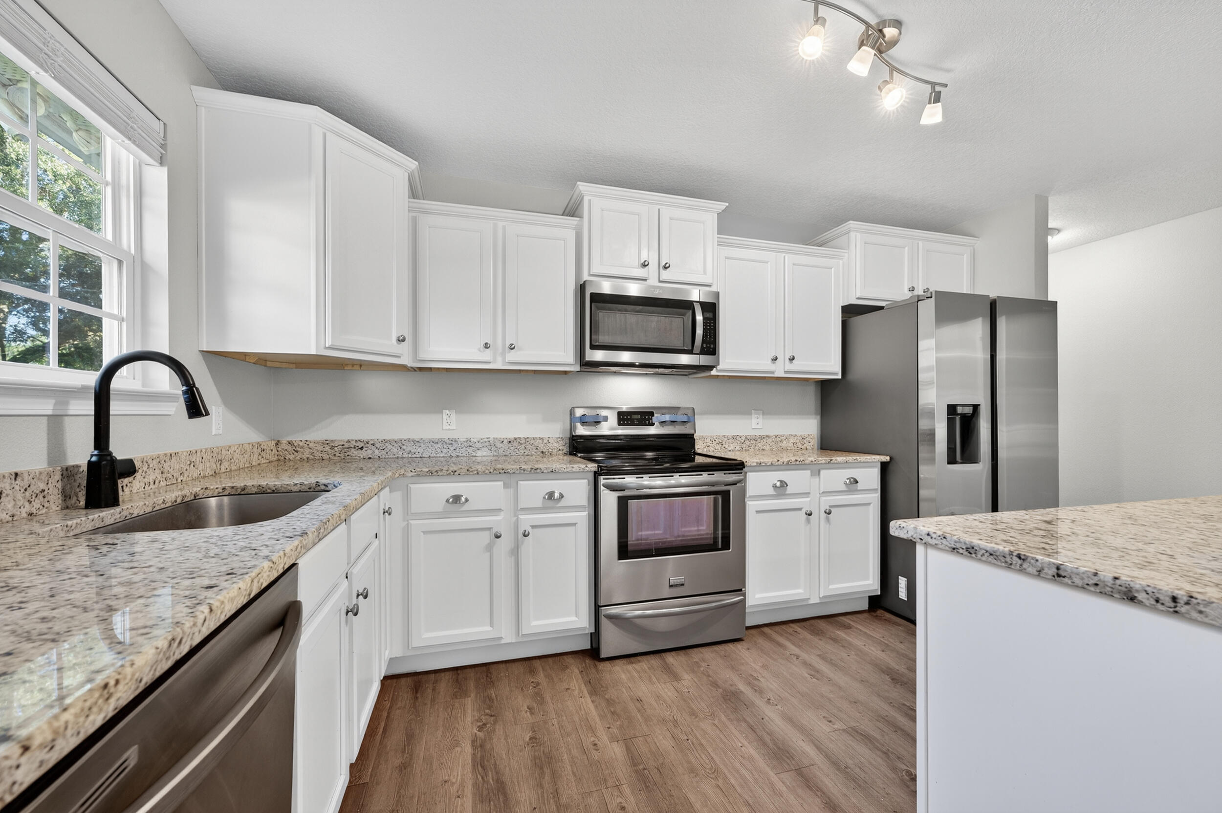 1833 Gainer Avenue Baker, FL 32531 - Photo 7 of 43 a kitchen with stainless steel appliances granite countertop a stove top oven a refrigerator a sink and dishwasher with wooden floor