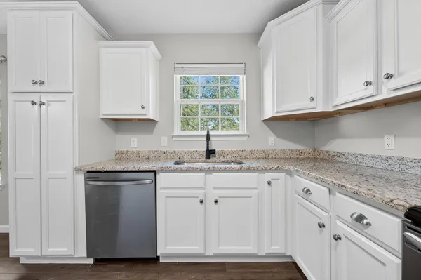 a kitchen with granite countertop white cabinets and a sink