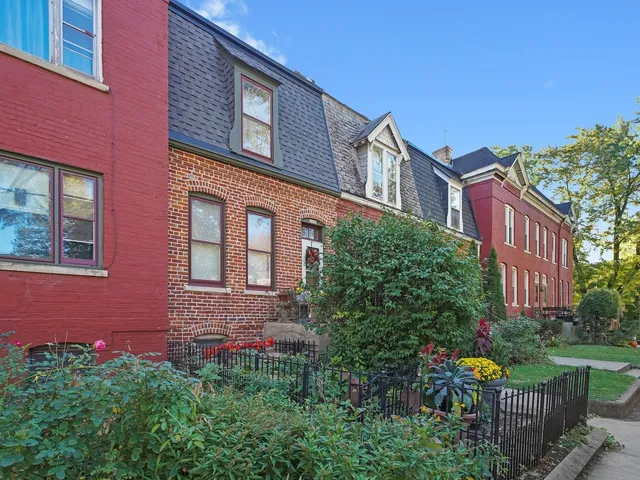 a front view of a multi story residential apartment building with yard and bench