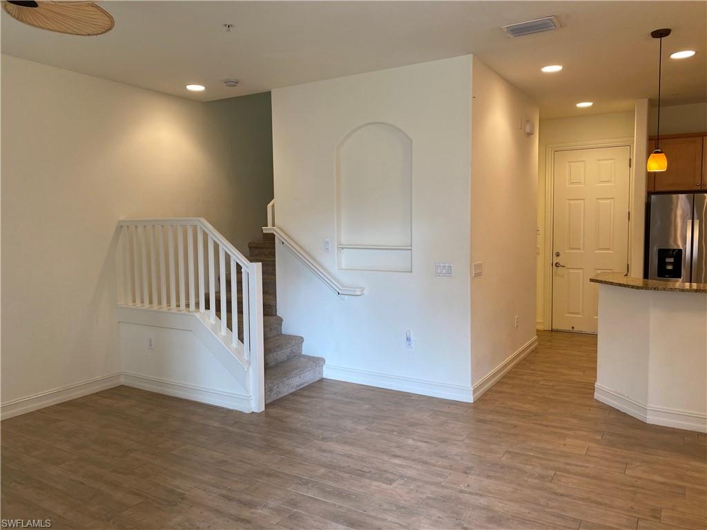 9151 Delano Street, Unit 9702 Naples, FL 34113 - Photo 5 of 14 an empty room with wooden floor and windows