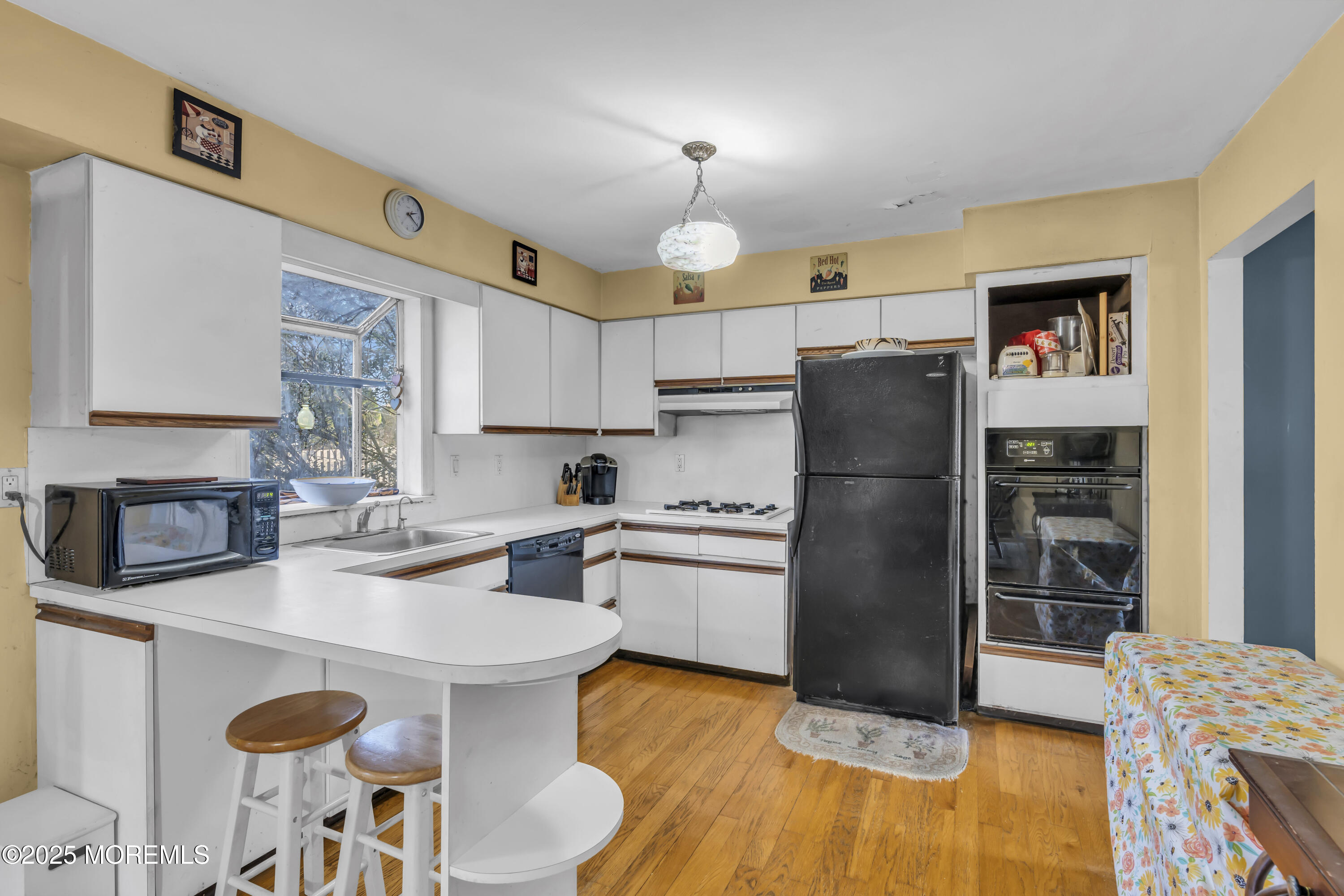 7 Whalepond Road Oakhurst, NJ 07755 - Photo 13 of 23 a kitchen with a refrigerator a stove a sink dishwasher and a dining table with wooden floor