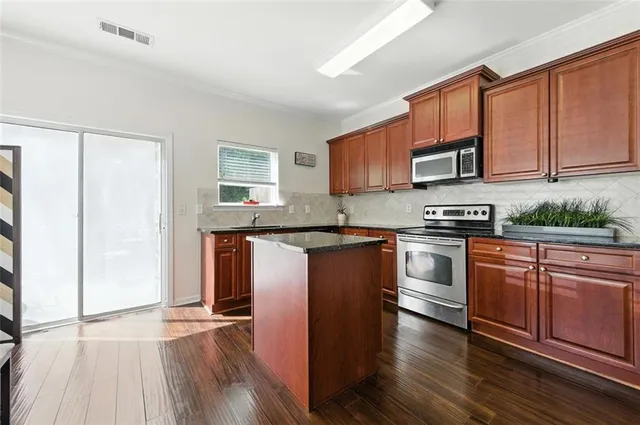 a kitchen with granite countertop wooden floors a stove and a microwave