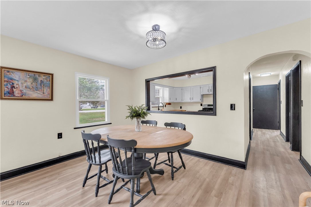 7320 Avon Belden Road North Ridgeville, OH 44039 - Photo 12 of 33 Dining space with arched walkways, light wood finished floors, and a chandelier