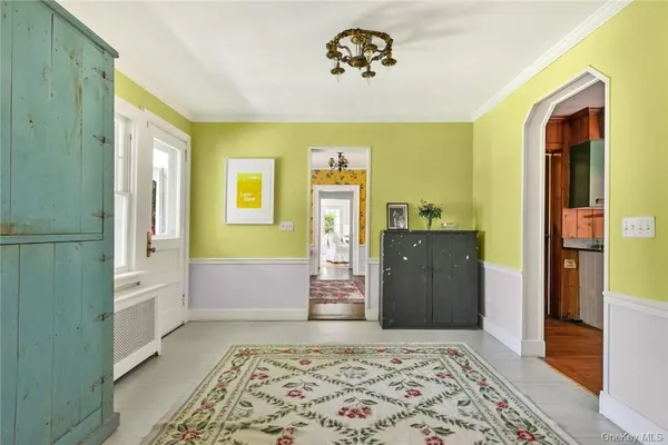 a living room with a dresser and chandelier