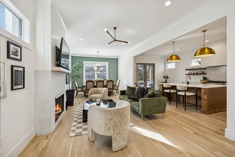 a kitchen with stainless steel appliances granite countertop a sink a stove a dining table and chairs with wooden floor