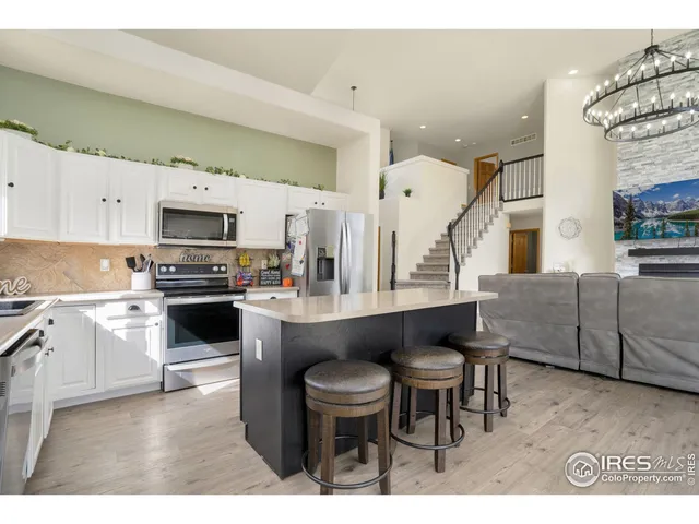 a kitchen with stainless steel appliances kitchen island granite countertop a table chairs sink and cabinets